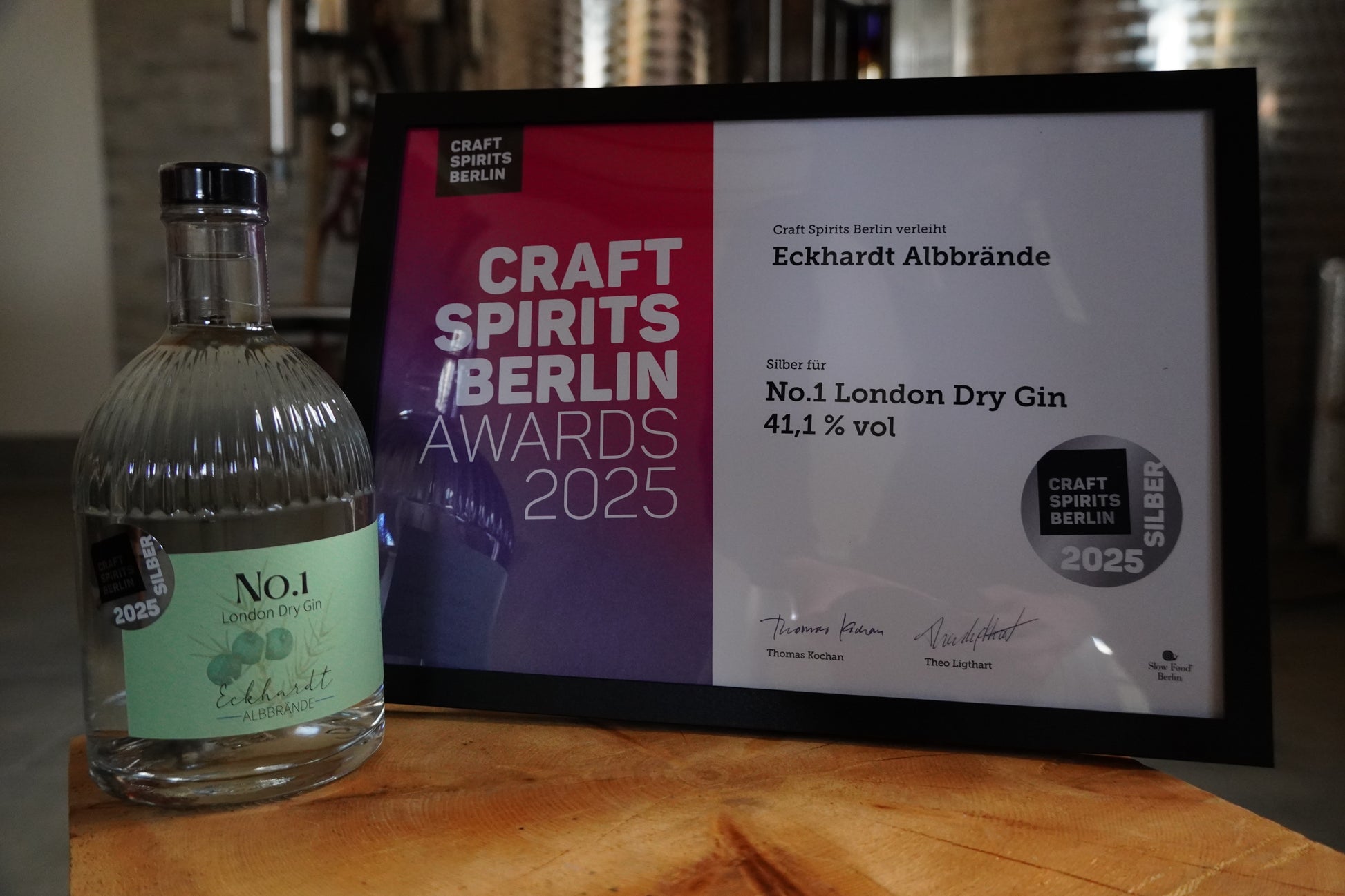 Flasche mit London Dry Gin No.1 von Eckhardt Albbrände auf einem Holztisch und neben einer Urkunde.
